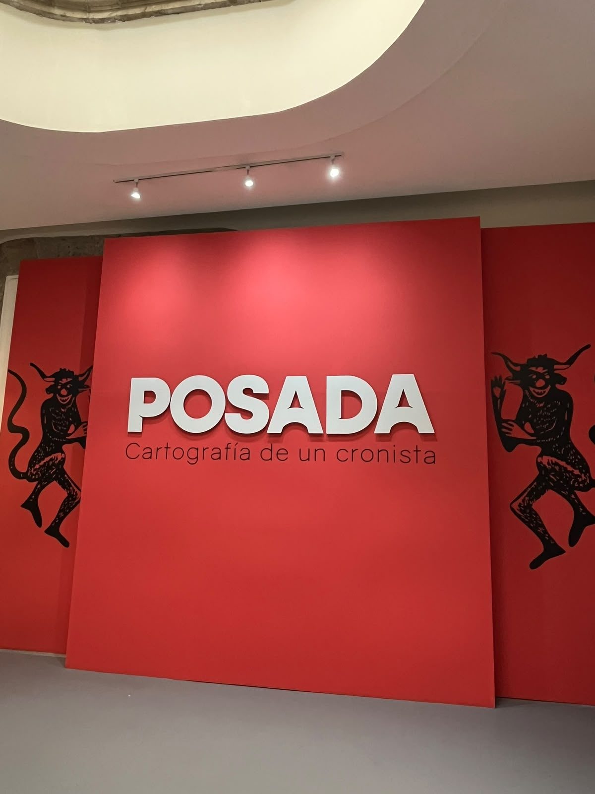 Muro rojo de la exposición POSADA. Cartografía de un cronista en el Munae con los diablitos danzantes de Posada a los lados