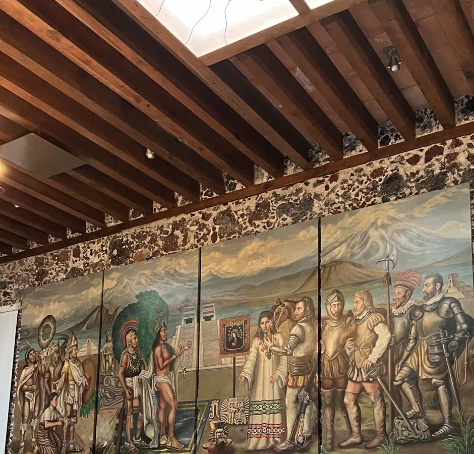 Pintura en cuatro paneles sobre un muro de piedra volcánica en Café de Tacuba, con guerreros mexicas, un templo, soldados españoles y volcanes al fondo