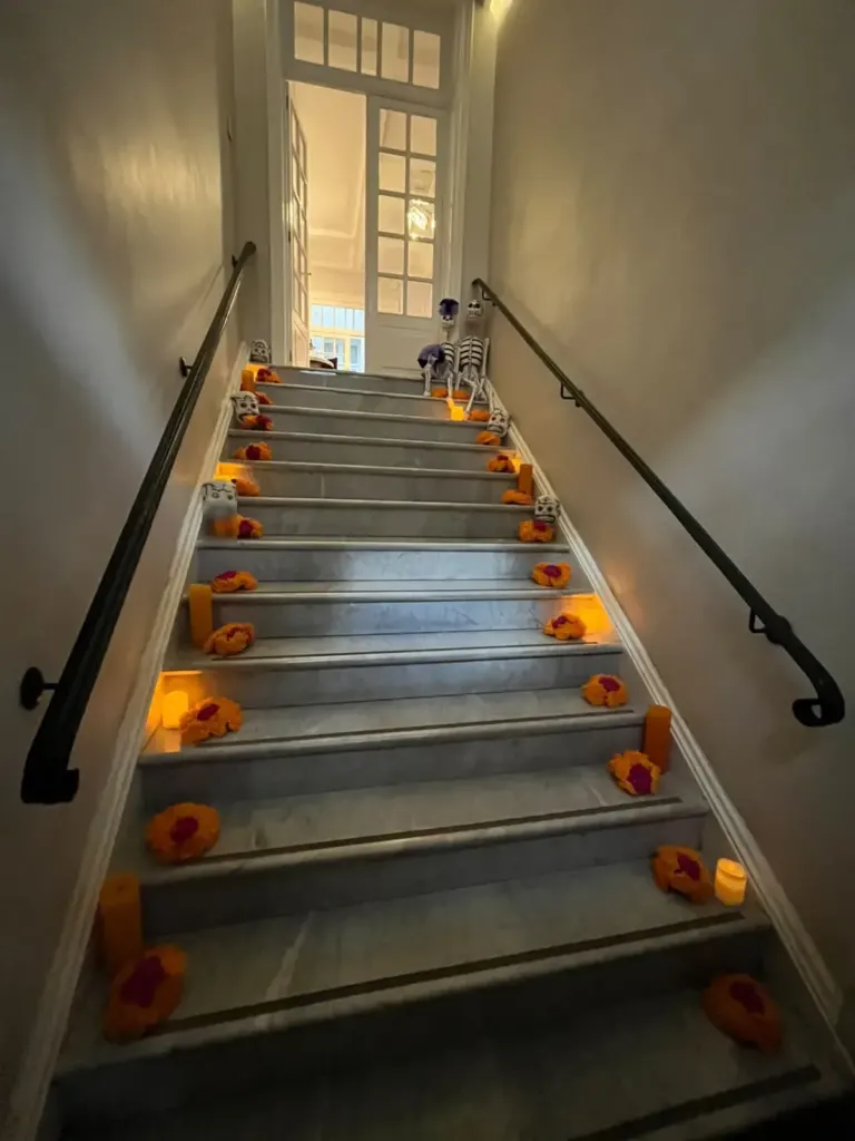 Escalera de Casa Goliana con flores de cempasúchil y velas en cada escalón por Día de Muertos