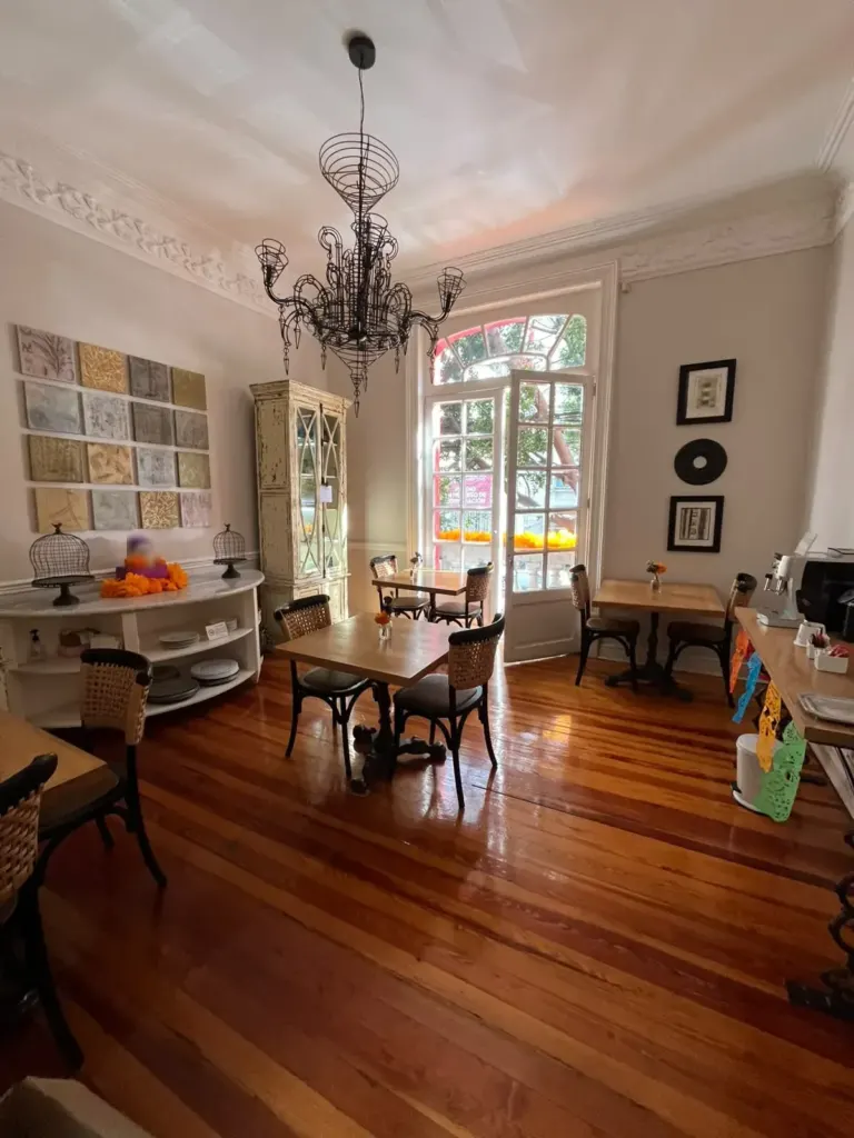 Comedor compartido de Casa Goliana con candil, mesas de madera, vitrina y ventanales