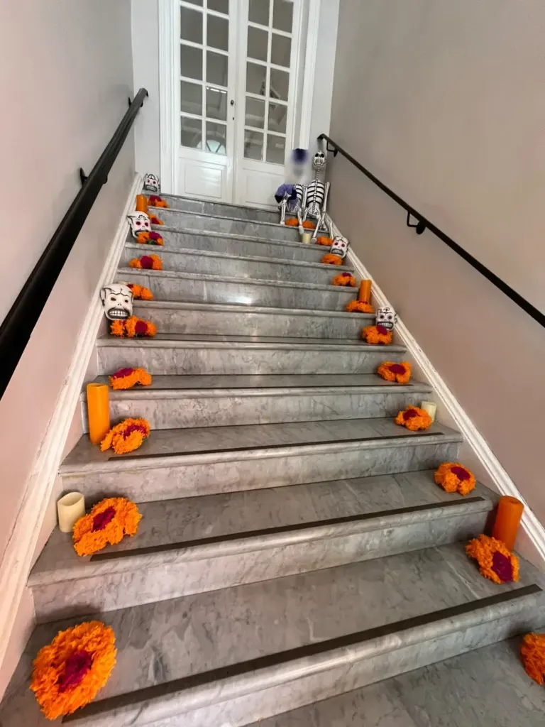 Escalera de Casa Goliana con flores de cempasúchil naranjas en los escalones y luz natural
