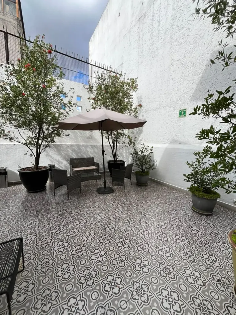 Terraza de Casa Goliana con sombrilla, sillones de exterior, macetas con árboles y piso de mosaico