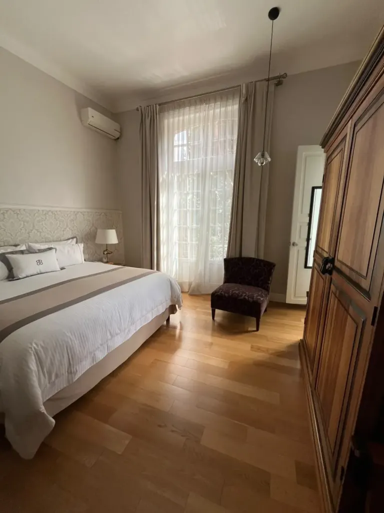 Habitación de Casa Goliana con cama king, sillón de terciopelo y ropero de madera