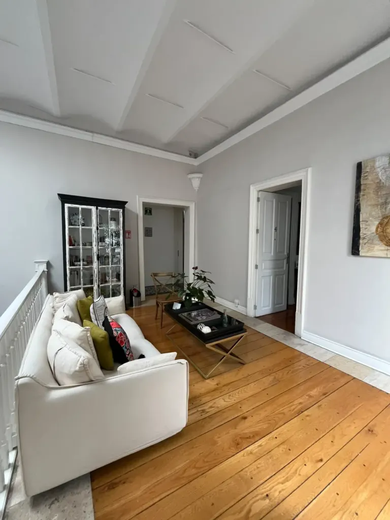 Sala de estar de Casa Goliana con sofá blanco, mesa de centro, vitrina y piso de duela