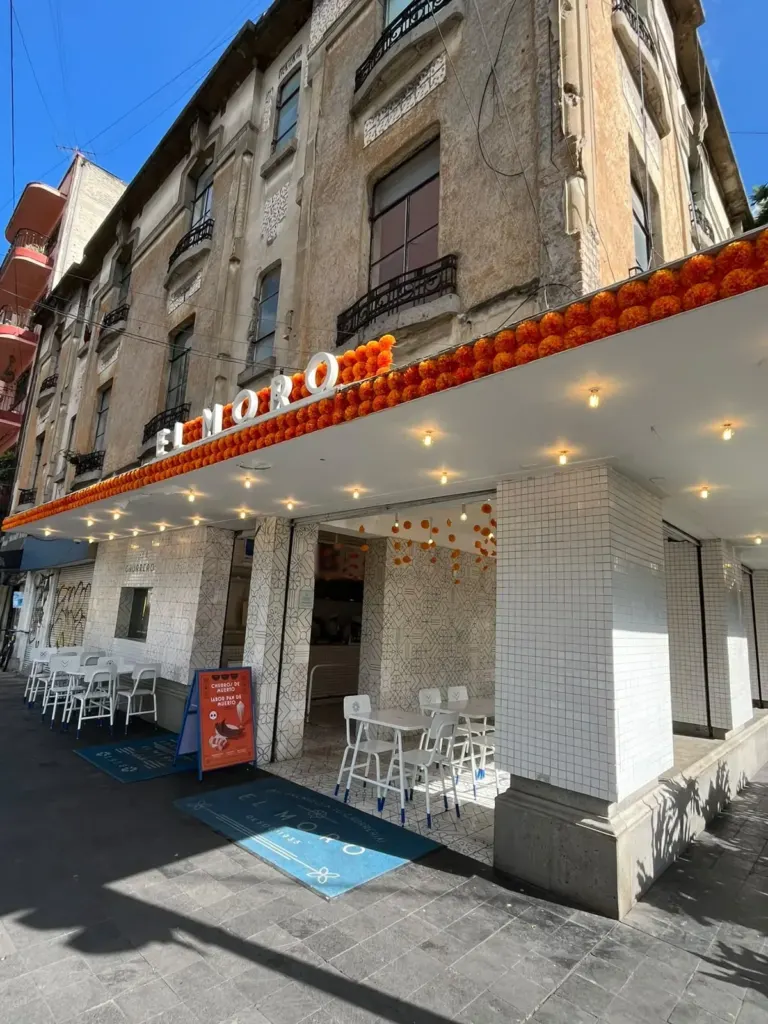 Fachada de Churrería El Moro en Álvaro Obregón, Roma Norte, con marquesina y mesas en la banqueta