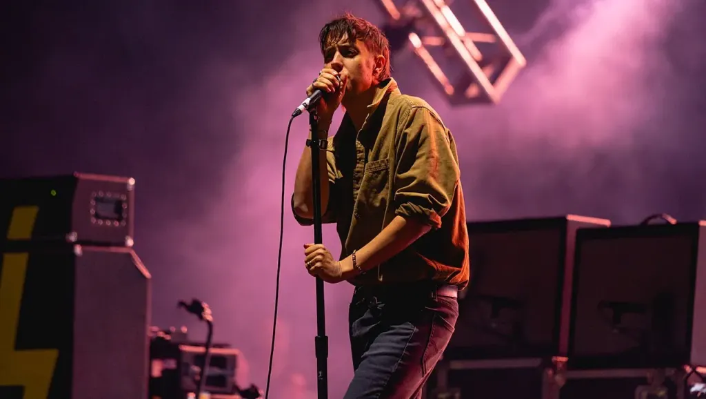El vocalista de The Strokes canta con el micrófono en el escenario del Corona Capital bajo luz morada