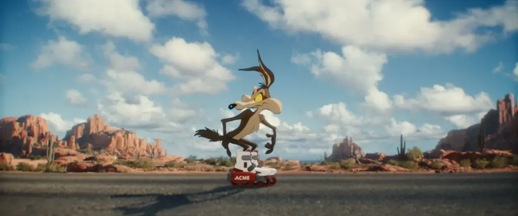 Wile E. Coyote sobre unos patines cohete ACME en una carretera del desierto con mesetas rojas al fondo