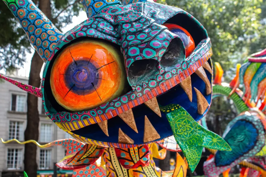 Alebrije monumental de colores con ojos grandes y dientes exhibido en una calle de la Ciudad de México