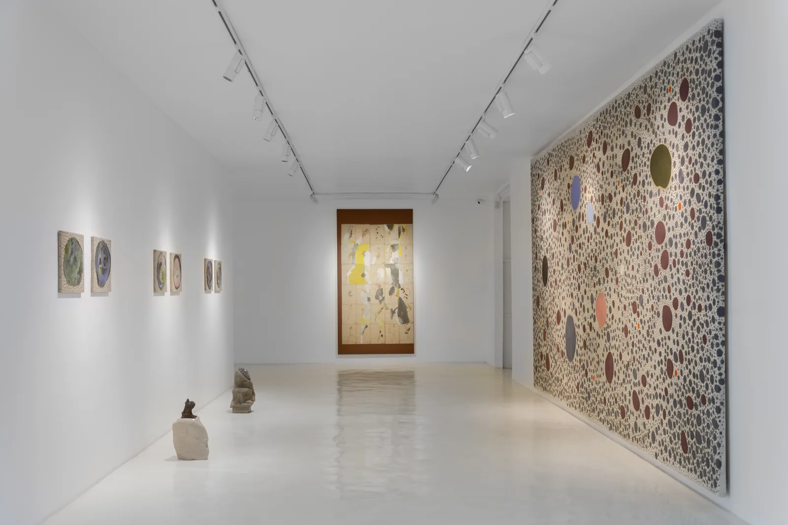 Pasillo de la galería con cerámicas Jars de James Brown en el piso y un lienzo de puntos en la pared