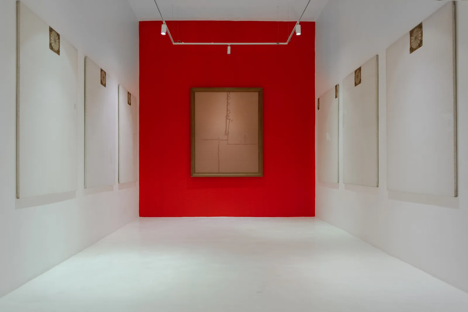 Sala con muro rojo y una obra al centro, rodeada de lienzos claros, en la expo Y la muerte no tendrá dominio