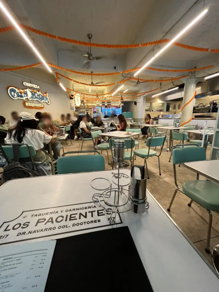 Interior de Los Pacientes: comedor con sillas turquesa y cempasúchil