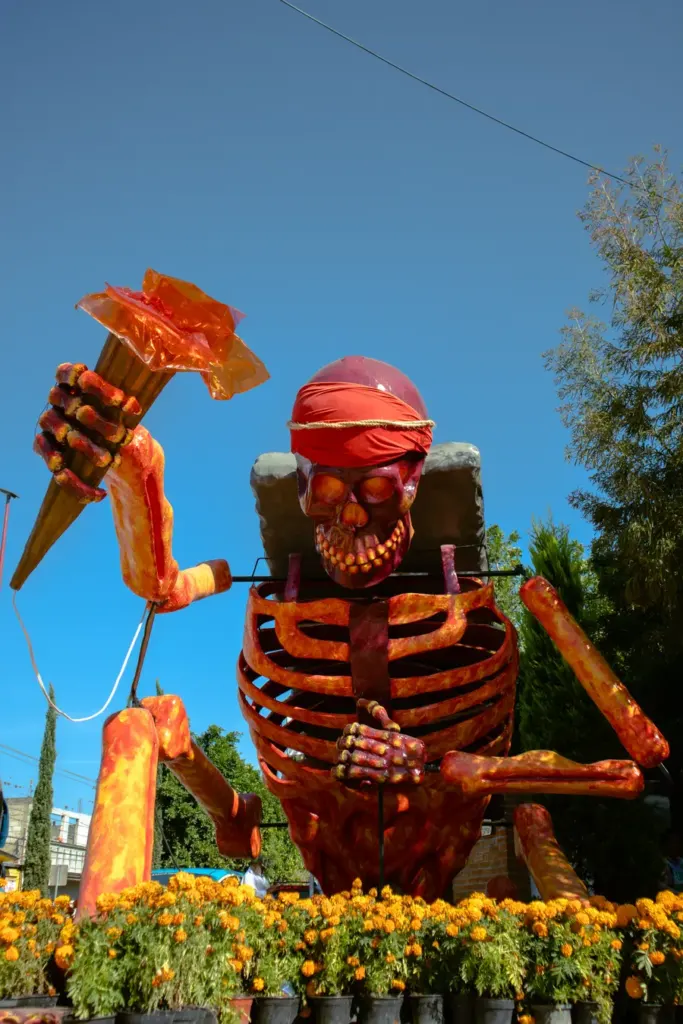 Figura monumental de calavera estilo Día de Muertos rodeada de flores de cempasúchil en la Ciudad de México