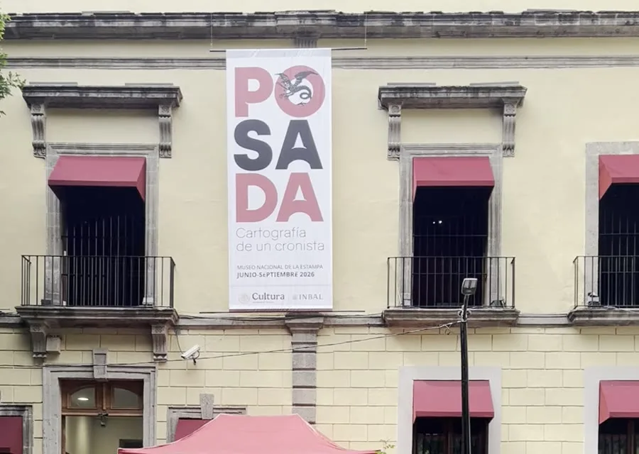 Fachada amarilla del Museo Nacional de la Estampa con balcones de toldos rojos, una lona vertical de la exposición de Posada y una carpa roja con el nombre del museo