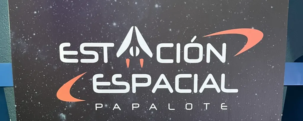 Letrero de la Estación Espacial Papalote con letras blancas y naranjas sobre un fondo de estrellas