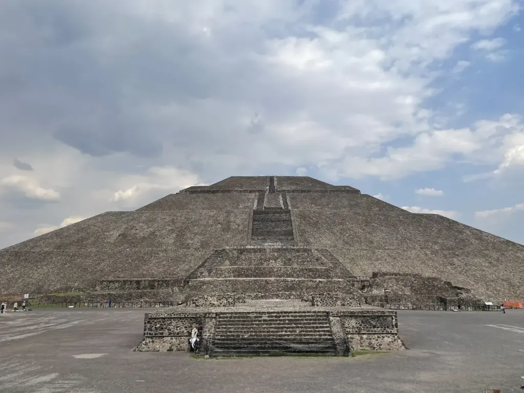 Pirámide del Sol de Teotihuacán vista de frente desde la explanada, bajo un cielo nublado