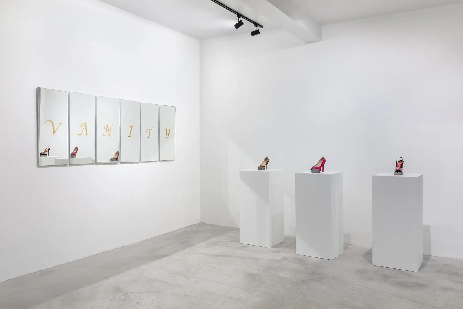 Instalacion Vanity de Teresa Serrano: seis espejos con la palabra VANITY en dorado y tres zapatos de tacon sobre pedestales blancos