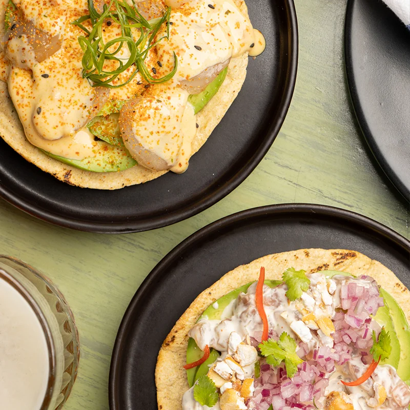 Tostadas de cebiche con salsa de ají en platos negros en Yakumanka